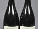 two bottles of red wine sitting next to each other on a table