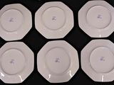 six white plates with blue designs on them on a black surface