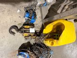un seau jaune auquel sont attachées des chaînes, à côté d'une fourche jaune