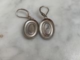 a pair of silver earrings sitting on top of a marble counter