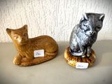 deux figurines de chats assis l'un à côté de l'autre sur une table