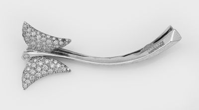 un gros plan d'une broche en forme de nœud ornée d'un diamant, sur fond blanc