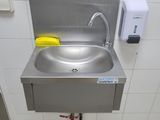 a stainless steel sink in a public restroom with a faucet and soap dispenser