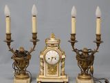 trois bougies et une horloge posées sur une table