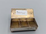an old silver box with a label on it sitting on a table