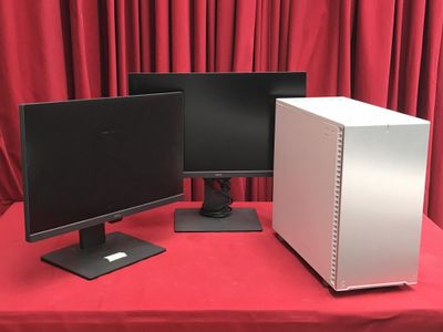 deux écrans d'ordinateur posés sur une table rouge, devant un rideau rouge