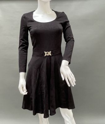 a mannequin wearing a black dress and hat with a gold broochet