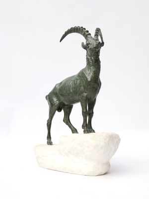 statue of a goat on a rock on a white background