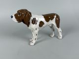 une figurine représentant un chien brun et blanc sur fond gris