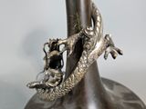 a silver vase with a dragon on it on a table
