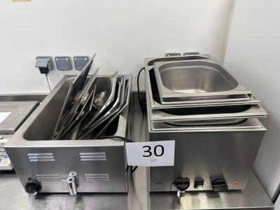 Plusieurs casseroles en acier inoxydable sont alignées sur une table