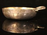 a silver bowl with a spoon on a black surface