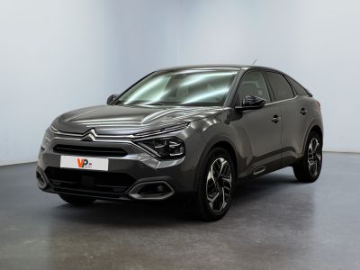 Une voiture grise est garée dans une pièce aux murs blancs.