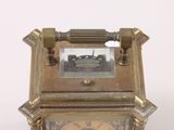 a small brass clock with roman numerals on the face