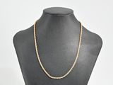 un collier en or en forme de corde autour du cou d'un mannequin
