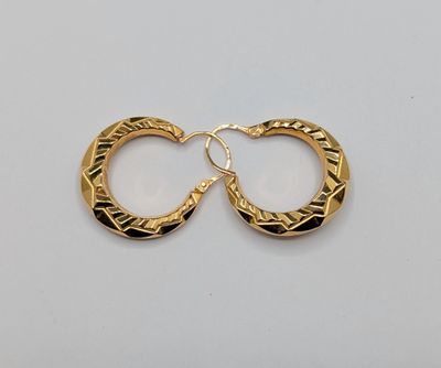 une paire de boucles d'oreilles en or sur fond blanc