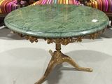 une image représentant une table avec un plateau en marbre vert et des pieds dorés