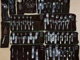 a lot of silverware on a table with a black bag