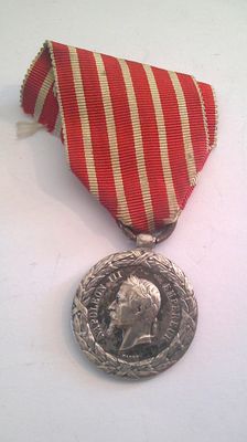 a silver medal with a red and white ribbon around it