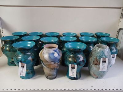 many vases that are on a shelf in a store