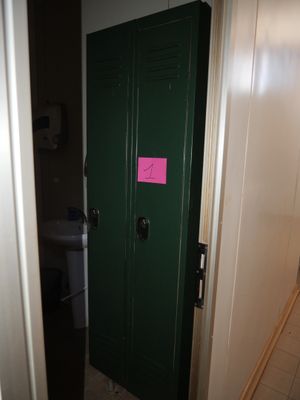 une porte verte sur laquelle est collé un autocollant rose, dans une salle de bains