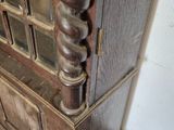 a tall wooden cabinet with a glass door on the top