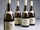 four bottles of wine are lined up on a table