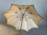 a white umbrella that is standing up against a wall