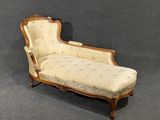 une chaise longue ancienne dont l'assise est recouverte d'un tissu à motifs floraux
