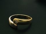 une bague en or sertie d'un diamant, posée sur une table
