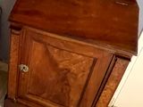 une petite armoire en bois située à côté des toilettes dans une salle de bains