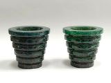 pair of green glass vases sitting on top of a white surface