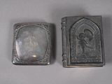 two antique silver cigarette cases sitting on top of a white table
