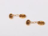 a close up of a pair of gold earrings on a white surface