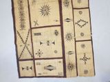 an old piece of cloth with designs on it hanging on a wall