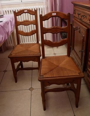 deux chaises en bois assises l'une à côté de l'autre dans une pièce