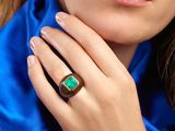 a woman wearing a ring with a green stone on it