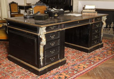 a black desk with a marble top in a room with a fireplace