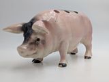 a small pig figurine that is standing on a white surface