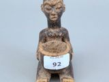 une vieille figurine représentant un homme tenant un bol de nourriture