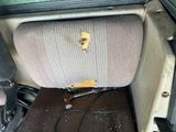 a dirty seat in the back of a car with a broken arm rest