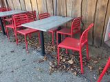 de nombreuses chaises et tables rouges devant une clôture en bois