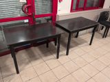 two tables and a chair in front of a red door
