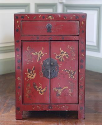 une image représentant une petite armoire rouge ornée de fleurs dorées