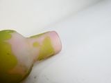 un vase vert et rose posé sur une surface blanche