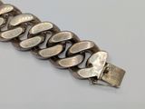 a close up of a silver chain bracelet on a white surface