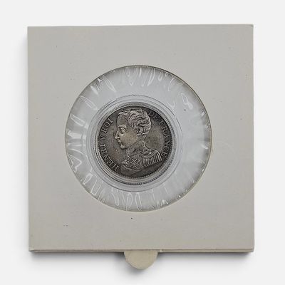 un gros plan d'une pièce de monnaie dans une boîte blanche posée sur une surface blanche