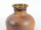 a brown vase that is sitting on a white surface