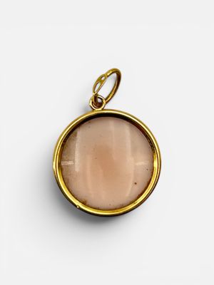 a gold plated pendant with a pink stone in the center