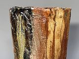 a brown and black vase sitting on a gray surface